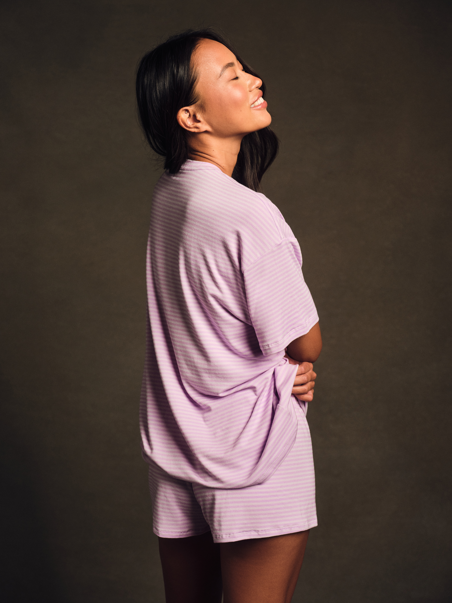 Woman wearing a light purple outfit against a dark background