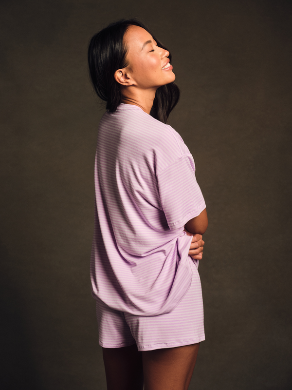 Woman wearing a light purple outfit against a dark background