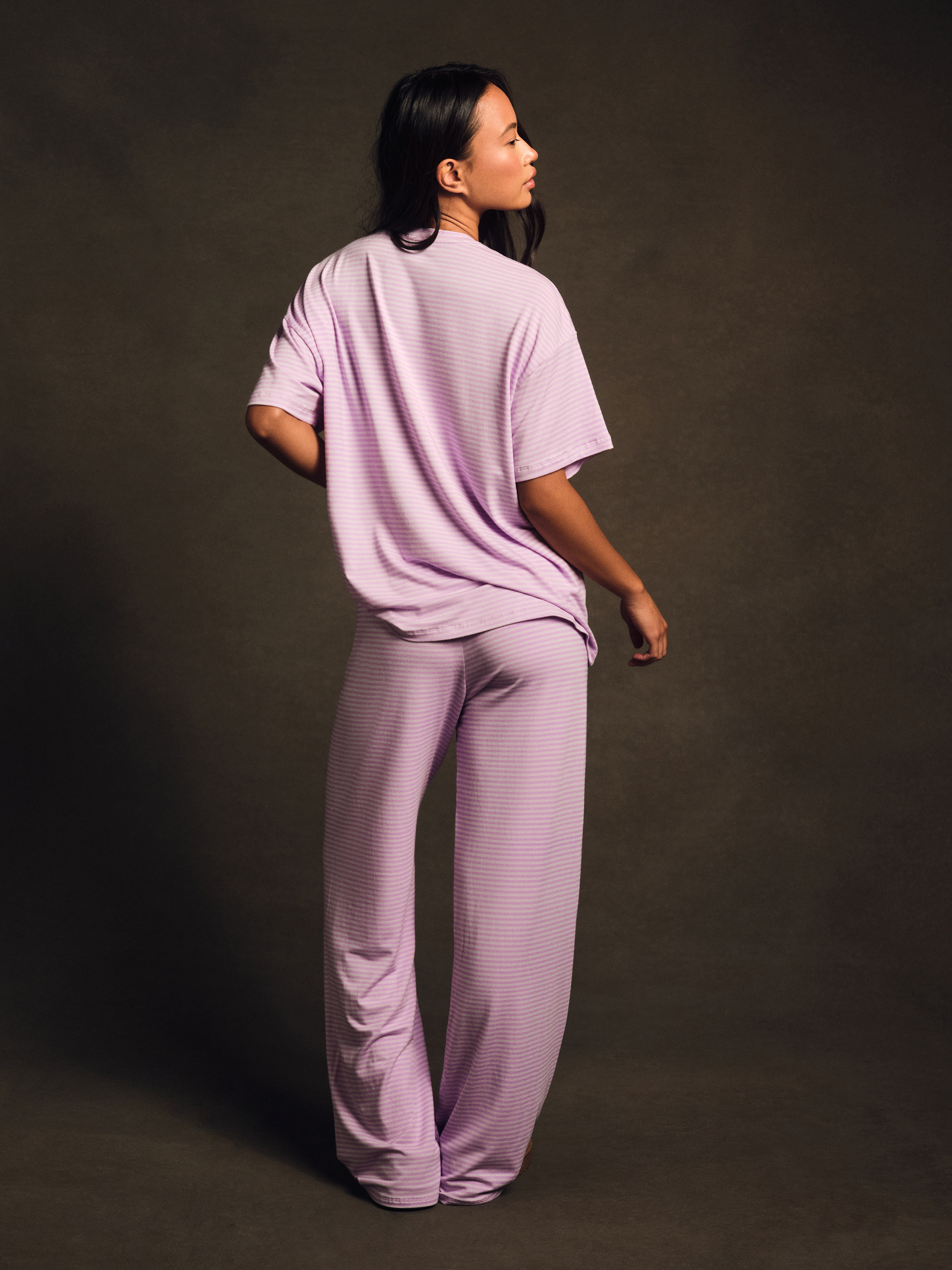 Person wearing a matching lavender outfit against a dark background
