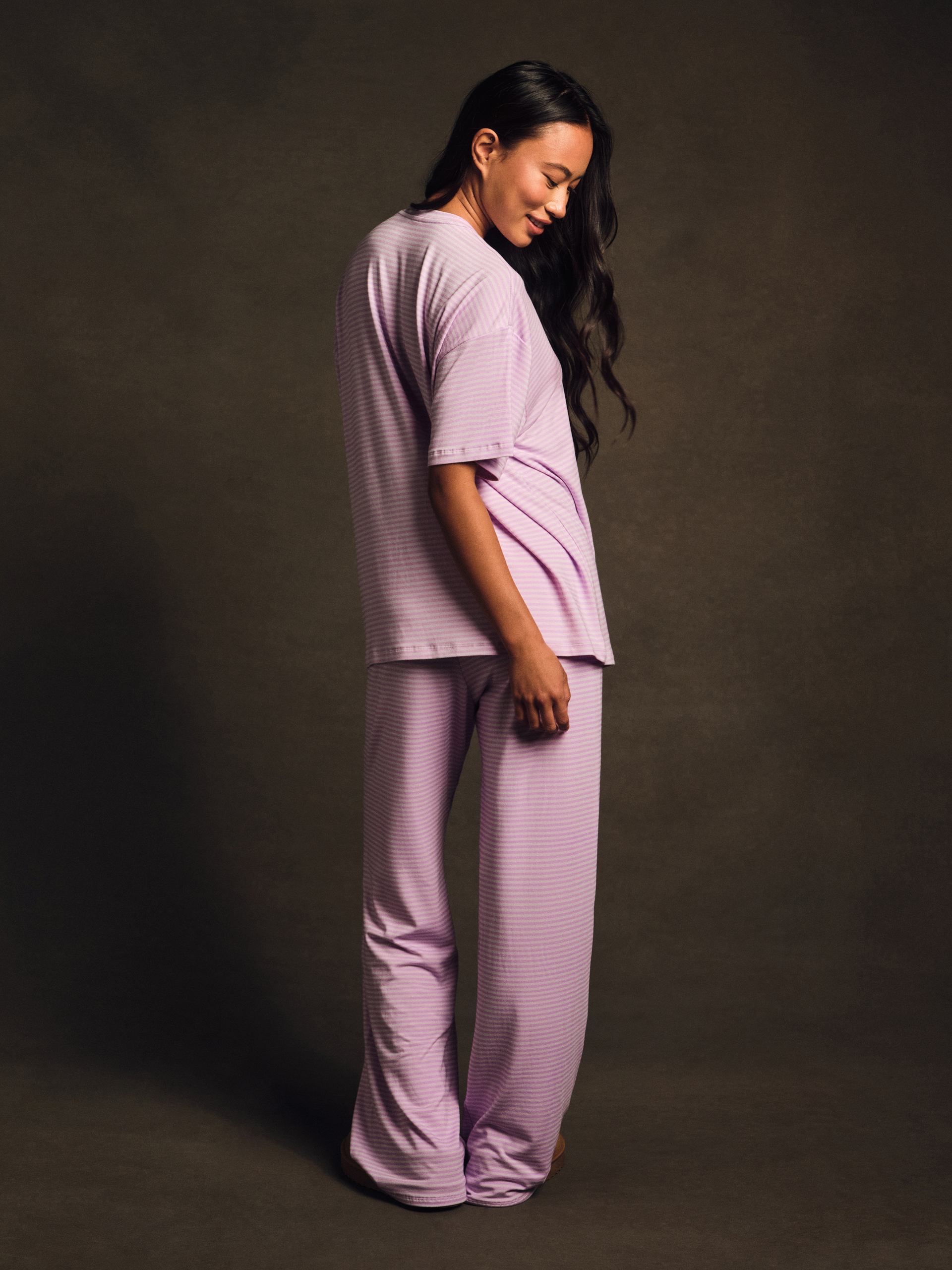 Woman wearing a matching lavender top and pants set against a dark background