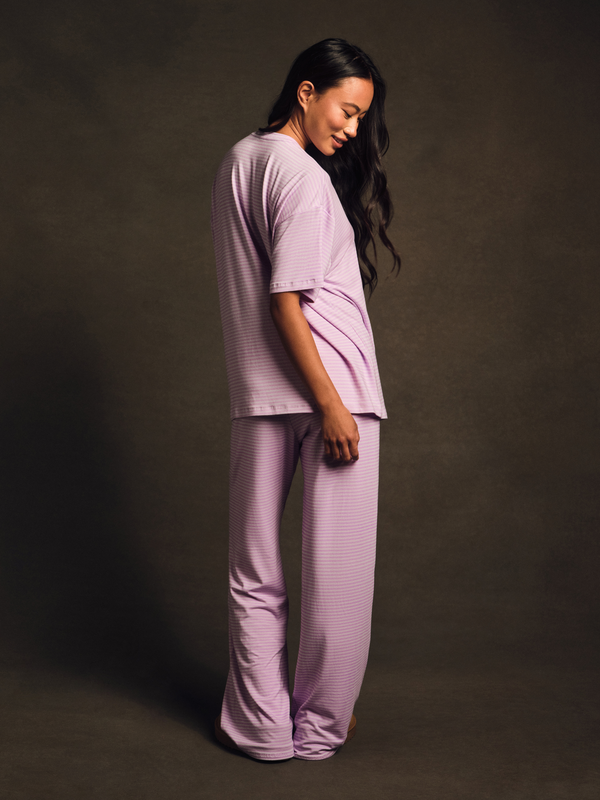 Woman wearing a matching lavender top and pants set against a dark background
