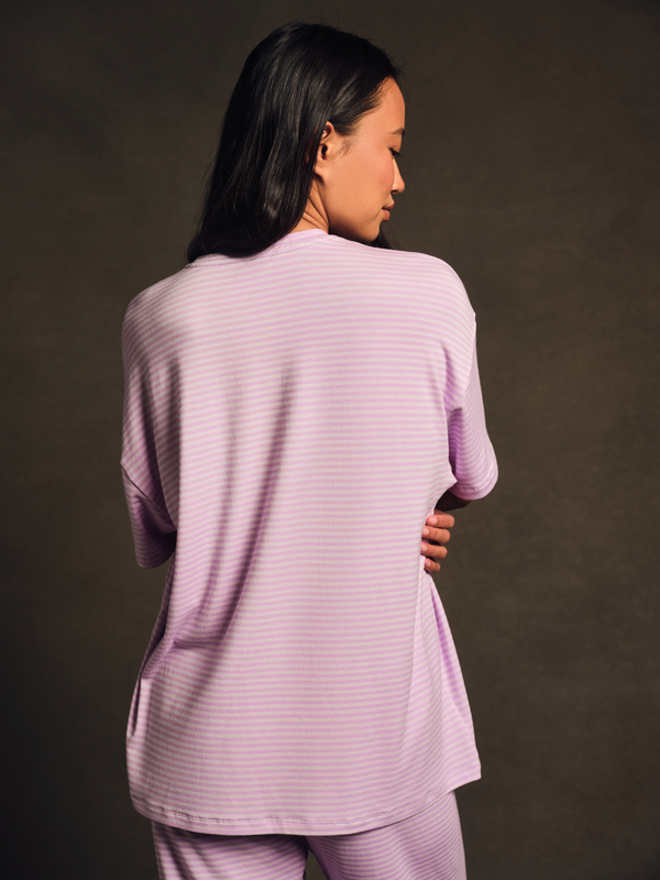 Woman wearing a light purple outfit against a dark background 