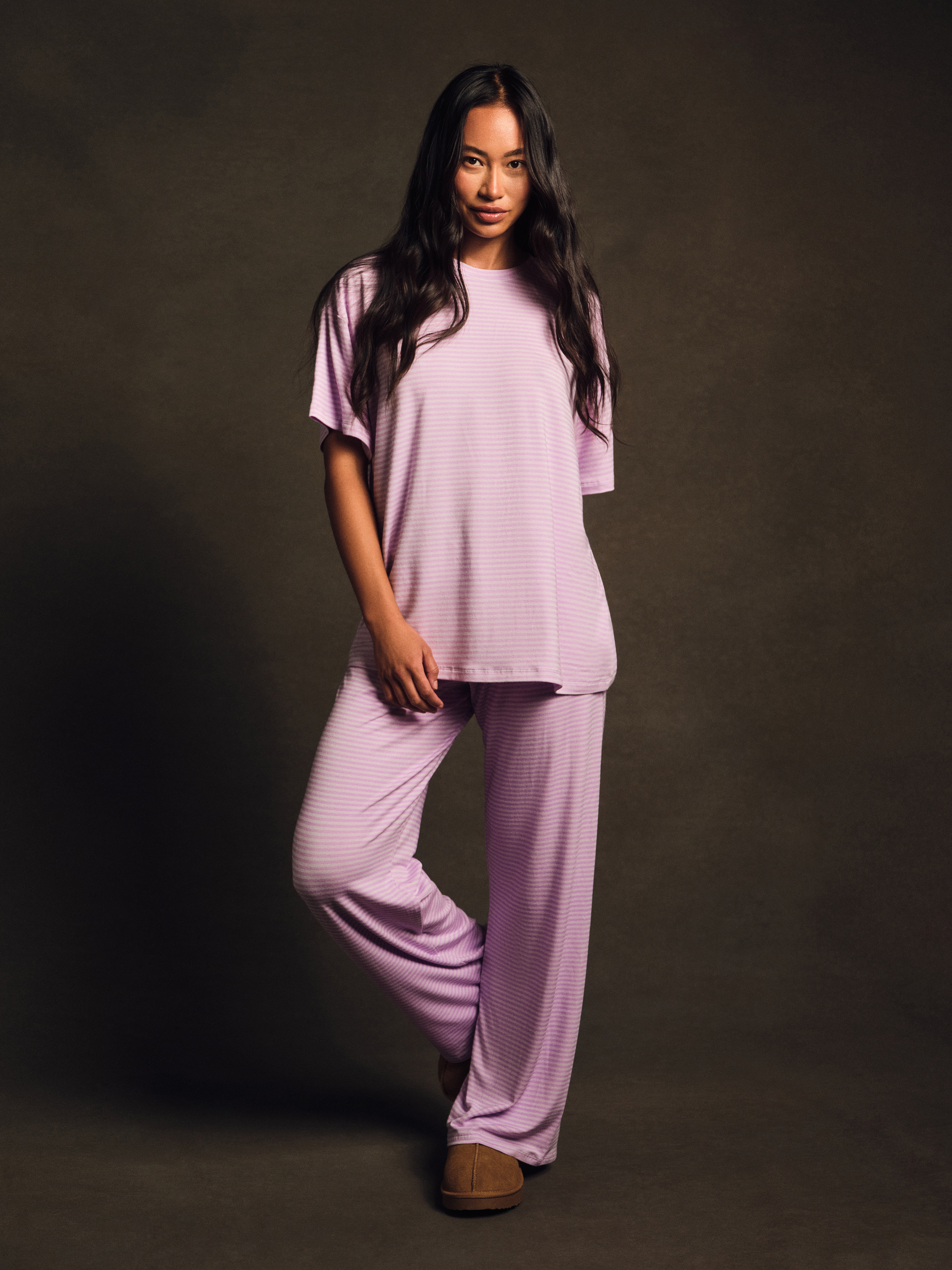 Woman wearing a light purple pajama set against a dark background