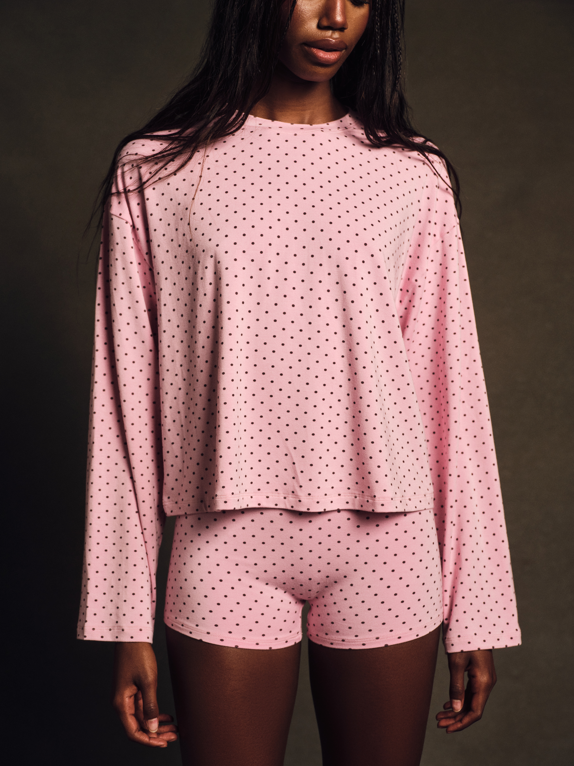 Person wearing a pink polka dot outfit against a dark background