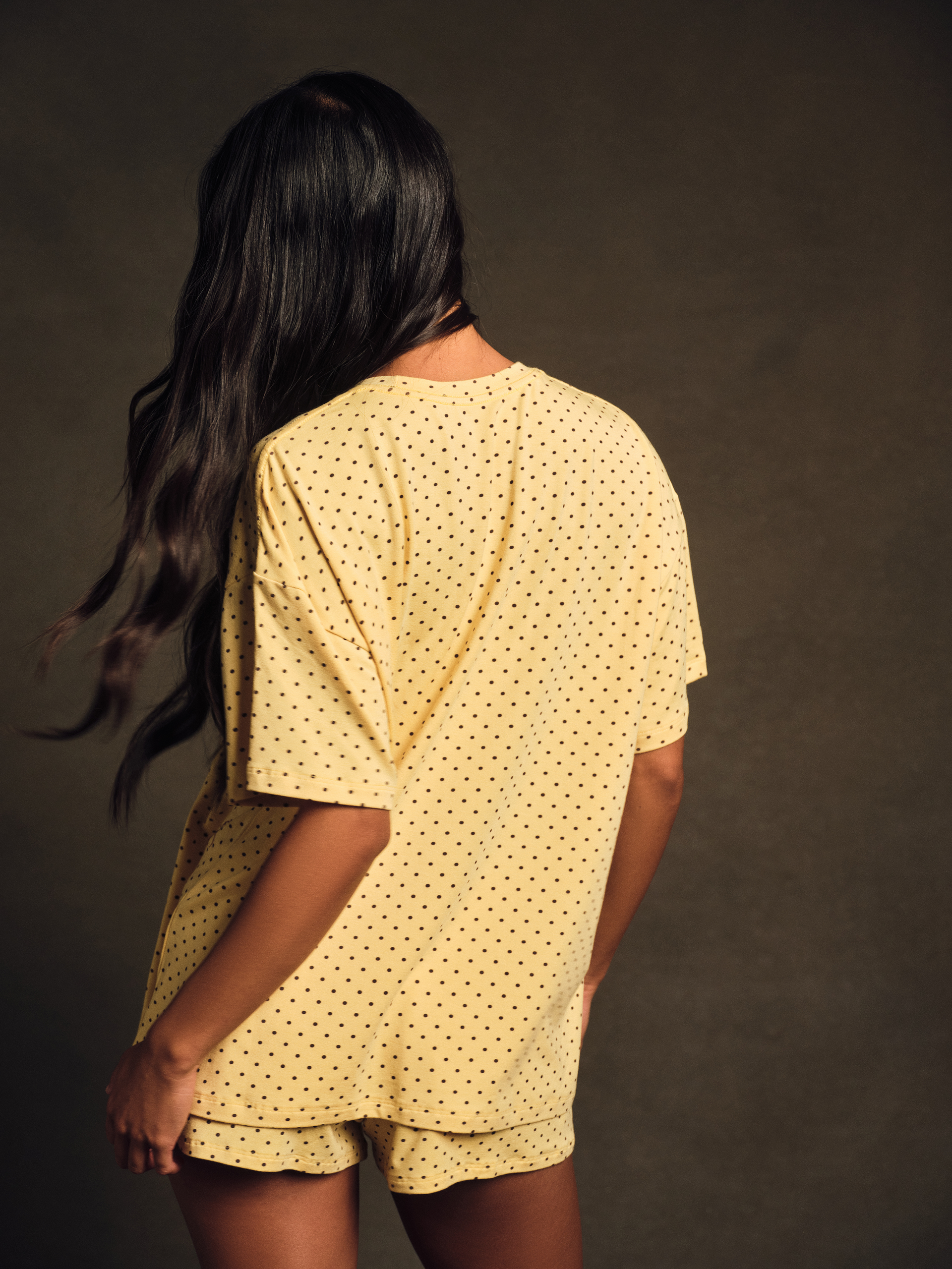 Woman wearing a yellow polka dot outfit with a dark background
