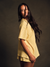 Woman wearing a yellow polka dot oversized boxy tee against a dark background