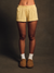 Person wearing yellow patterned shorts and brown slippers on a dark background