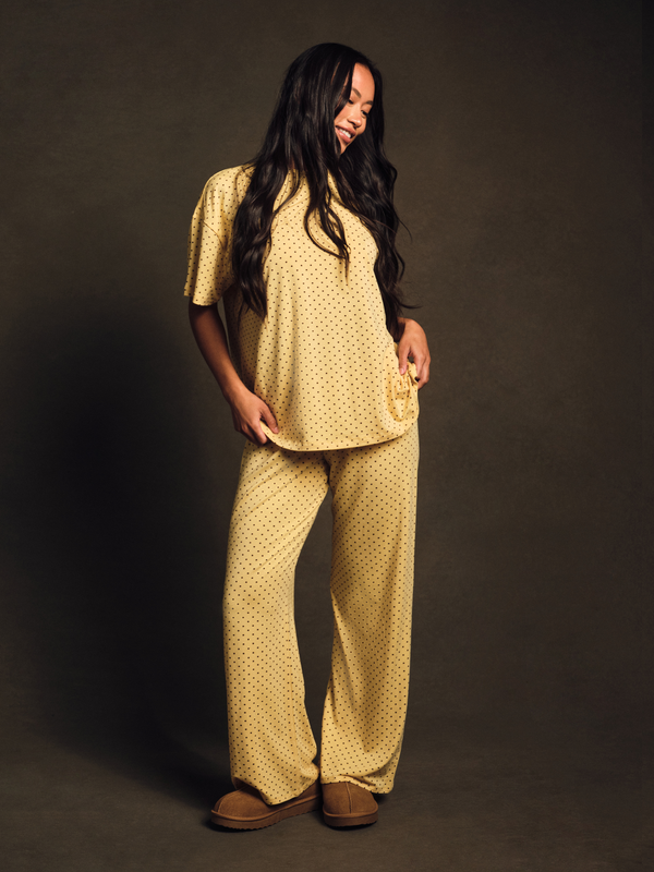 Woman wearing a yellow patterned outfit against a dark background 
