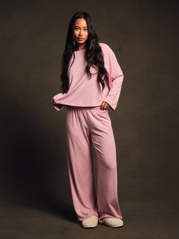 Woman wearing a pink polka dot pajama set against a dark background 