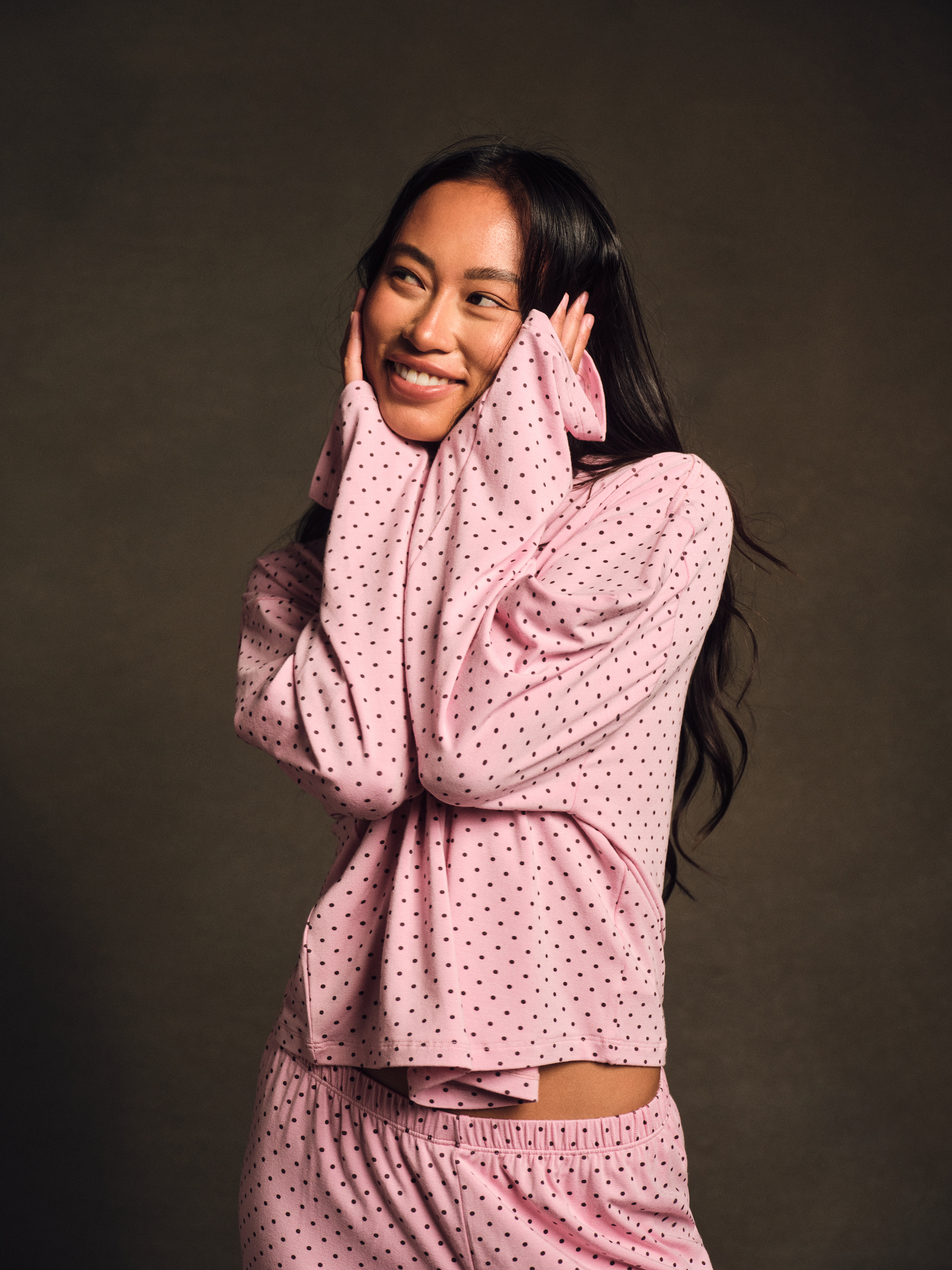 Woman wearing a pink polka dot outfit against a dark background <model-info>Amber wears a size S and is 5’½”, 22½” waist, 30B" bust.</model-info>