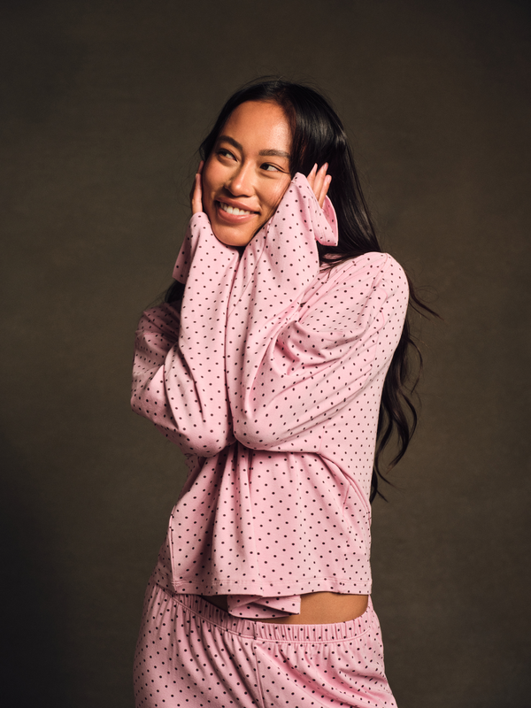 Woman wearing a pink polka dot outfit against a dark background 
