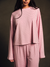 Person wearing a pink polka dot outfit against a dark background