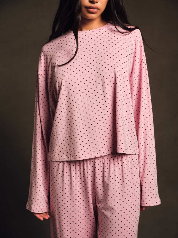 Person wearing a pink polka dot outfit against a dark background