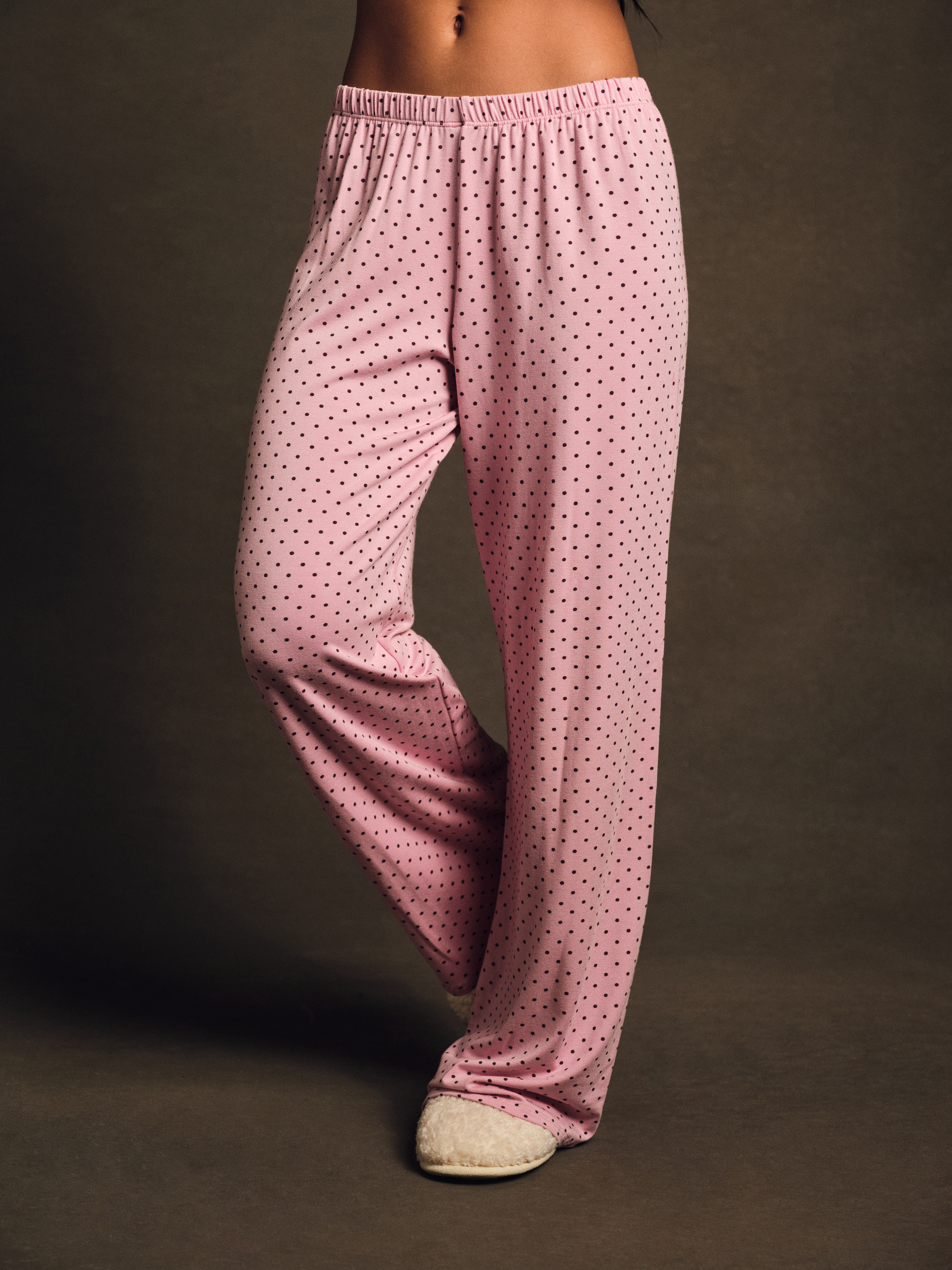 Pink polka dot pajama pants on a dark background