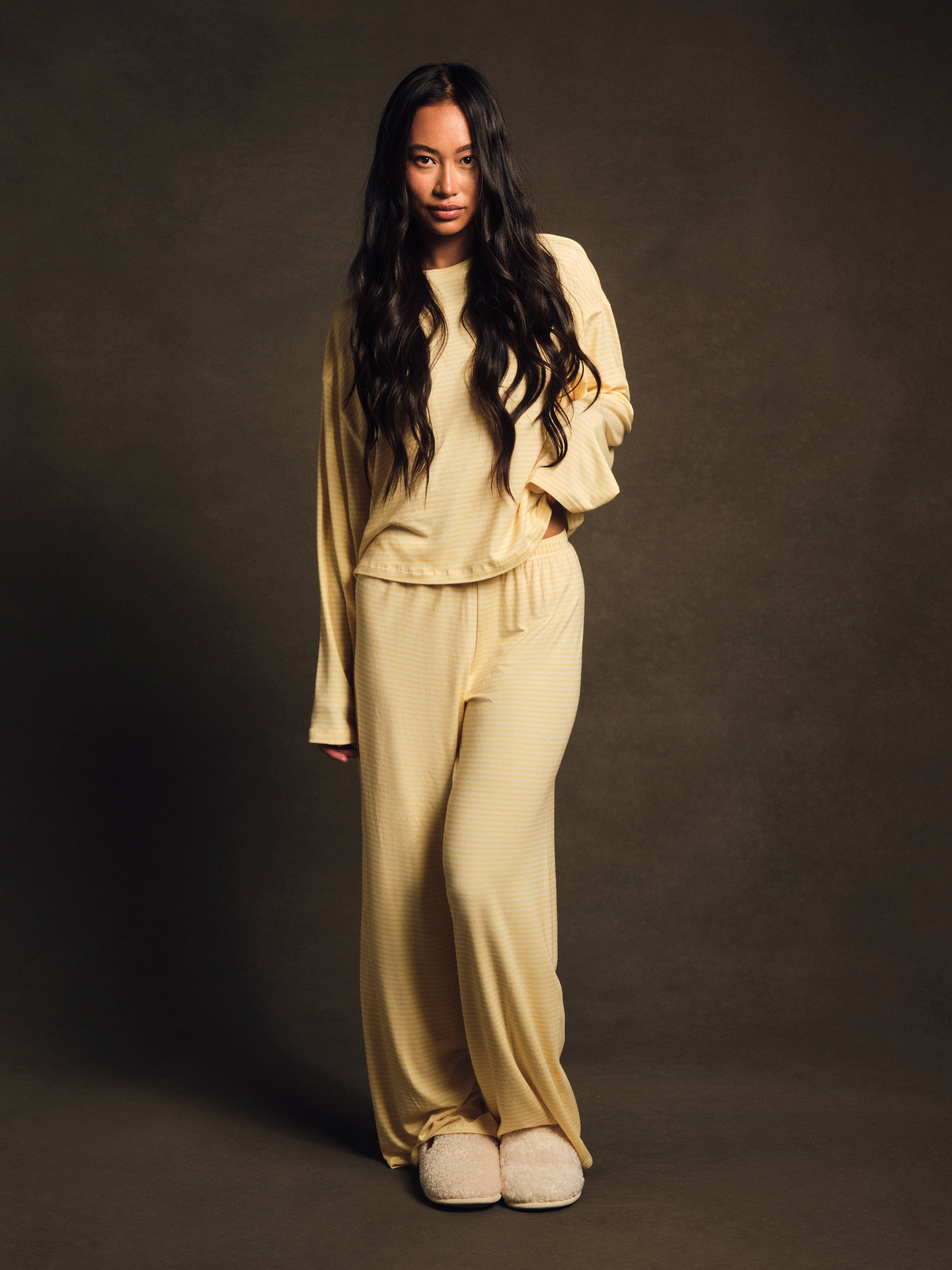 Woman wearing a beige tracksuit against a dark background 