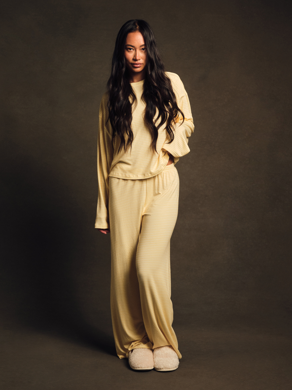 Woman wearing a beige tracksuit against a dark background 