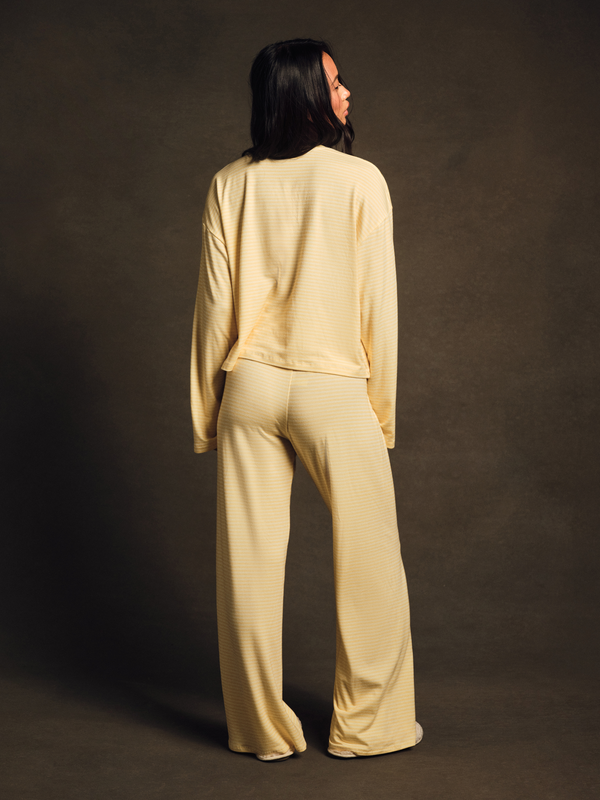 Woman wearing a beige outfit against a dark background
