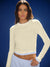Woman wearing a light-colored long-sleeve top against a blue background <model-info>Logan wears a size S and is 5’9½”, 24” waist, 32B bust.</model-info>