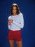 Woman wearing a white long-sleeve shirt and red shorts on a blue background <model-info>Logan wears a size S and is 5’9½”, 24” waist, 32B bust.</model-info>