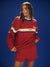 Woman wearing a red tracksuit with a logo on a blue background <model-info>Logan wears a size S and is 5’9½”, 24” waist, 32B bust.</model-info>