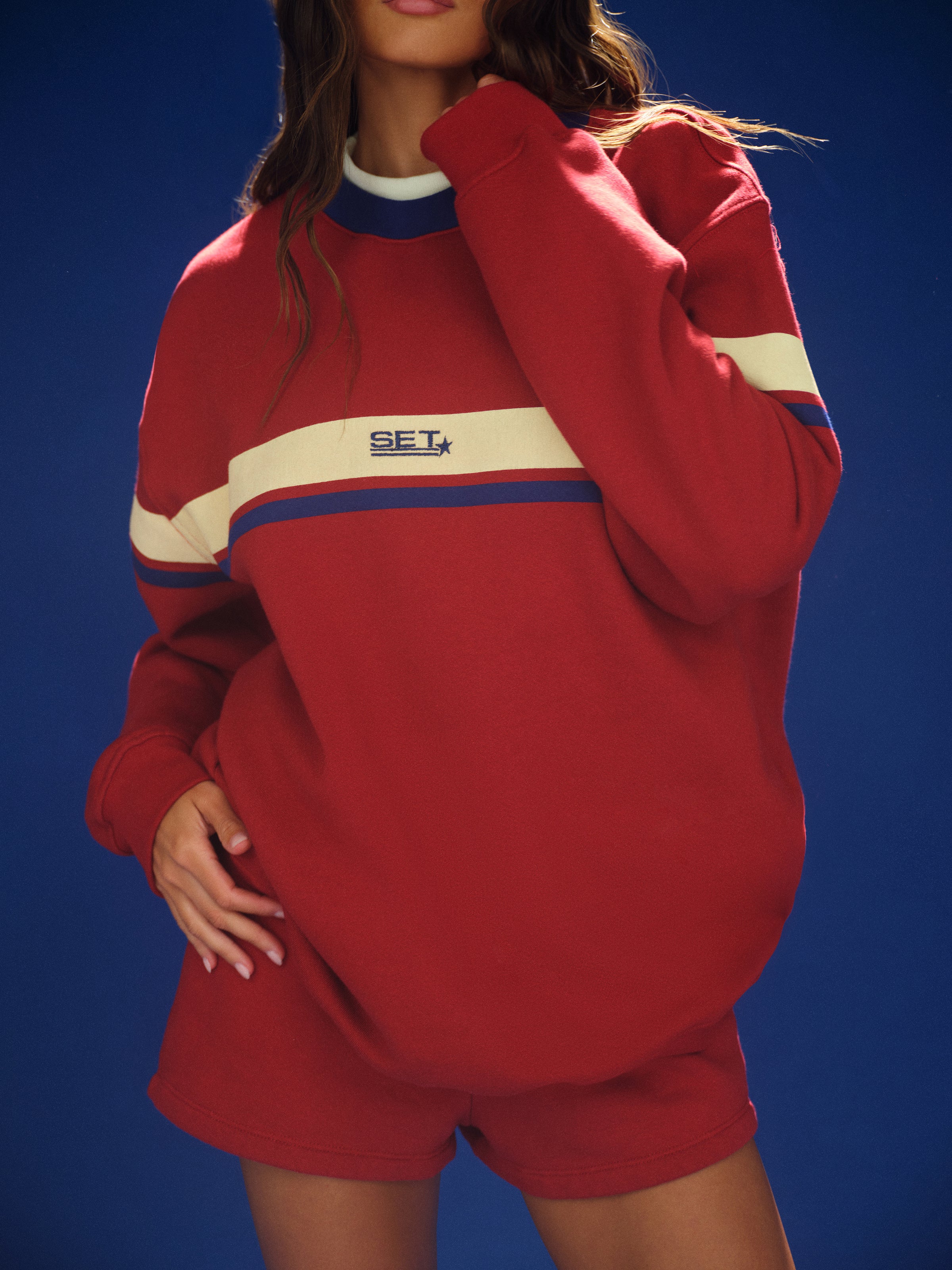 Person wearing a red tracksuit with a visible brand logo against a blue background
