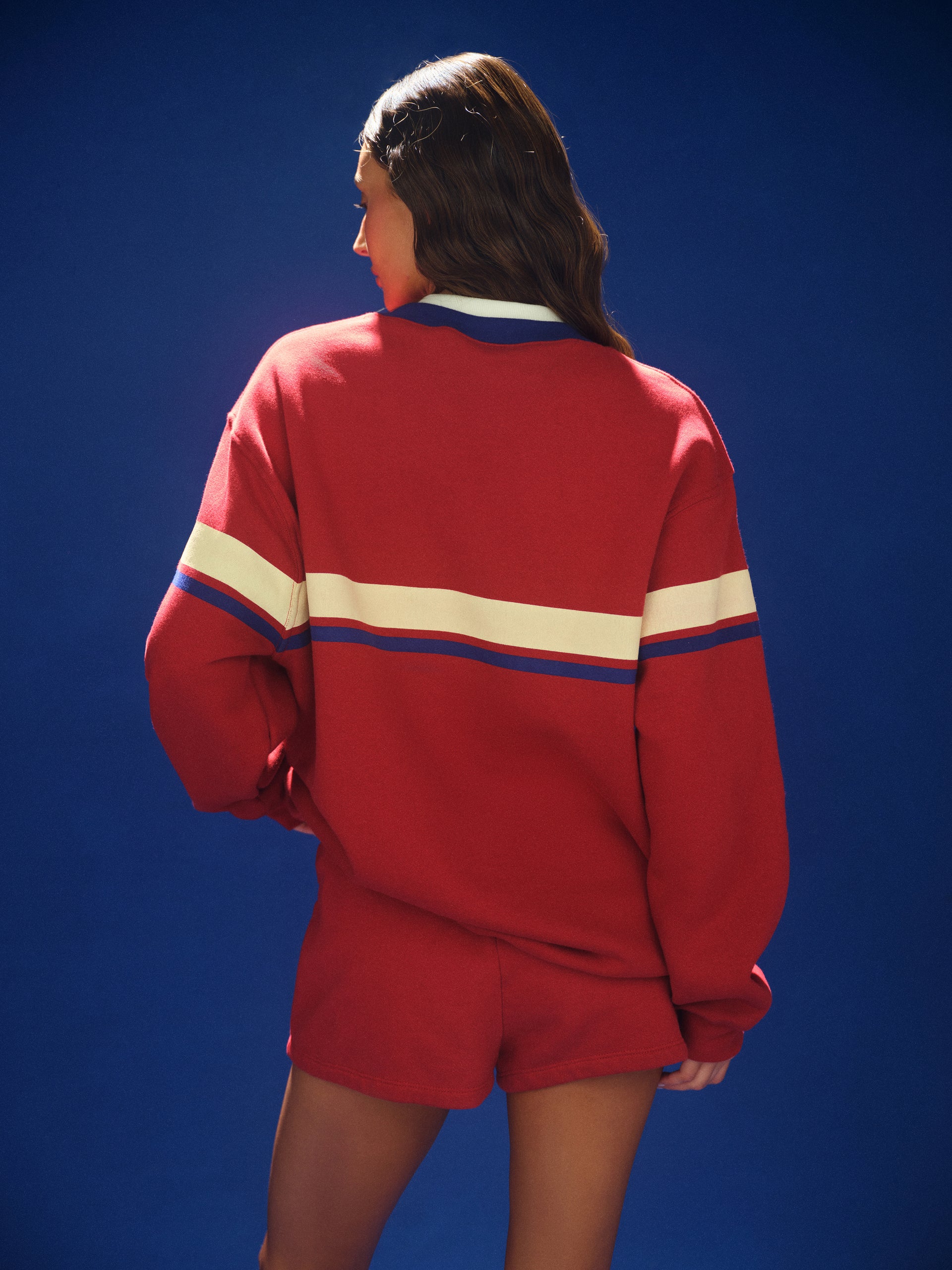 Person wearing a red tracksuit with white and blue stripes on a blue background