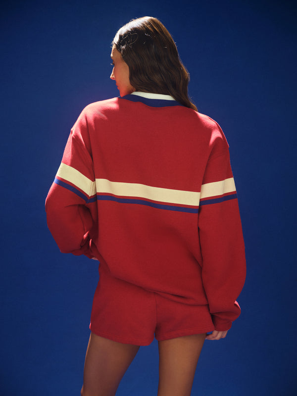 Person wearing a red tracksuit with white and blue stripes on a blue background