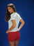 Woman wearing a white top and red shorts against a blue background