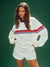 Woman wearing a white sweatshirt with red and blue stripes on a green background <model-info>Kushi wears a size S and is 5'8, 24” waist, 32C bust.</model-info>