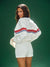 Woman wearing a white sweater with red and blue stripes and white shorts on a green background