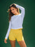Woman wearing a light blue long-sleeve top and yellow shorts against a green background <model-info>Kushi wears a size S and is 5'8, 24” waist, 32C bust.</model-info>