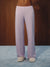 A person wearing light lavender striped lounge pants and fuzzy beige slippers, standing against a dark wood wall and blue carpet.