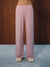 Pink wide-leg pajama pants with a small dark polka dot pattern, shown on a model from the waist down against a dark wood background and blue carpet.