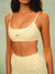 A woman wearing a matching cream-colored activewear set with brown polka dots, featuring a sports bra and high-waisted leggings, against a soft sage green background. <model-info>Meeya wears a size XS and is 5’7, 23” waist, 32B bust.</model-info> 