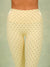 Close-up of a model wearing high-waisted leggings in a pale cream color with a small brown polka dot pattern, set against a solid sage green background.