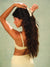 Model adjusting the Freckle Yellow polka dot claw clip in her long hair against a green background