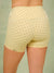 Close-up back view of a model wearing high-waisted yellow leggings with a brown polka dot pattern. The brand name 'SET' is printed in black near the left leg. <model-info>Raine wears a size M and is 5’8”, 29½” waist, 34” bust.</model-info>