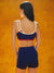 Woman wearing a blue sports bra and shorts set against an orange background