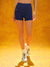 Person wearing blue athletic shorts and white sneakers on a yellow background