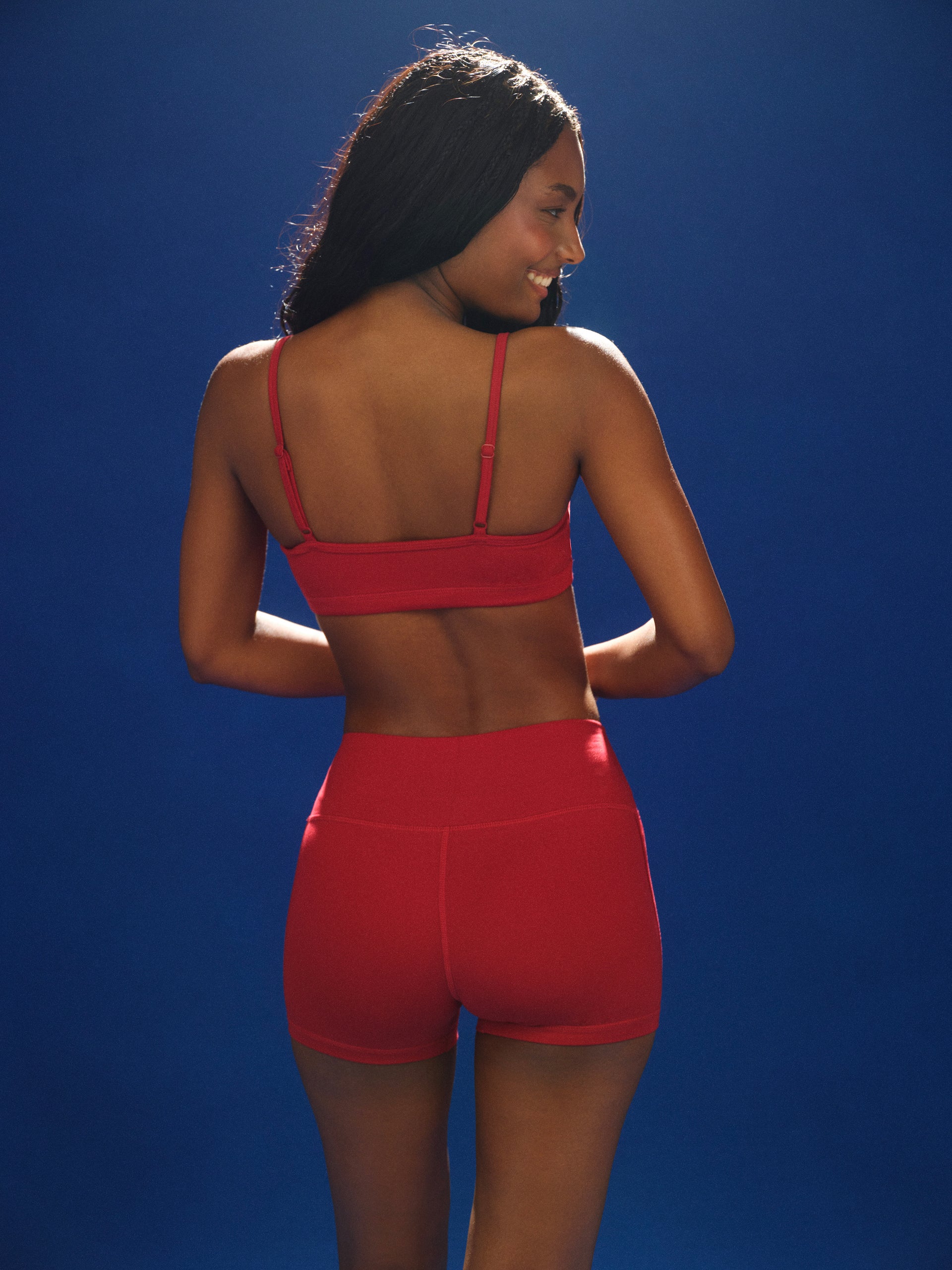 Person wearing a red sports bra and shorts set against a blue background