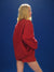 Person wearing a red sweatshirt against a blue background