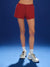 Person wearing red shorts and white sneakers on a blue background