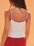Woman wearing a white tank top with red straps and red pants against an orange background