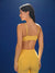 Woman wearing a yellow sports bra and leggings against a blue background