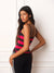 A woman posing in a bright red, black, and white striped athletic tank top and black track pants with white side stripes, set against a white paneled wall.