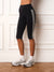Black ribbed biker shorts with double white side stripes, modeled on a person standing in front of a white paneled wall on a wood floor.