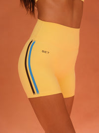 Yellow athletic shorts with blue and black accents on a brown background 