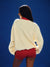 Person wearing a cream sweater and red shorts against a blue background