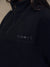 Close-up of a person wearing a dark navy quarter-zip fleece pullover with the word 'sport' embroidered on the chest.