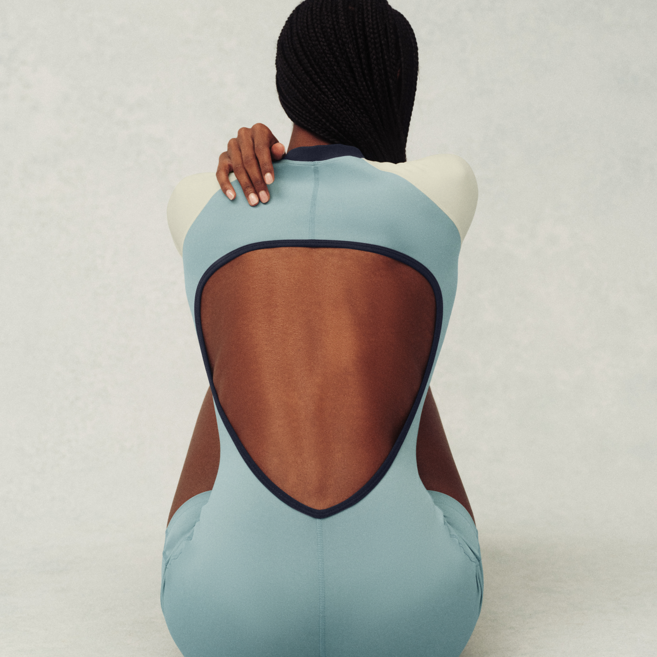 Mannequin wearing a light blue swimsuit with a brown back section on a plain background
